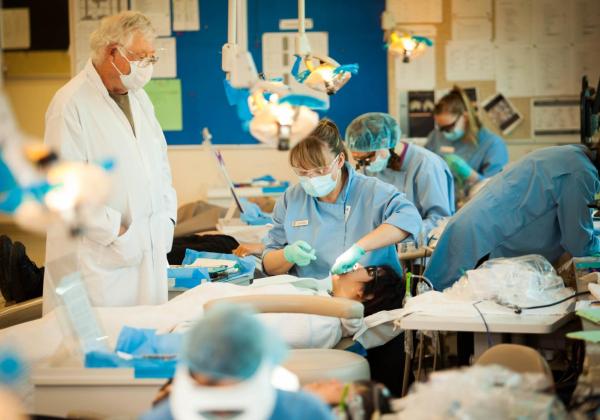 A female student assesses a patient while her instructor observes